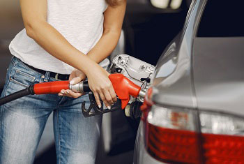 Woman holds a fuel pump next to her car, photo